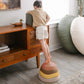 Child standing on Tiny Land® Stepping Stones - Sunset Hues in a room with wooden furniture and large cushions.