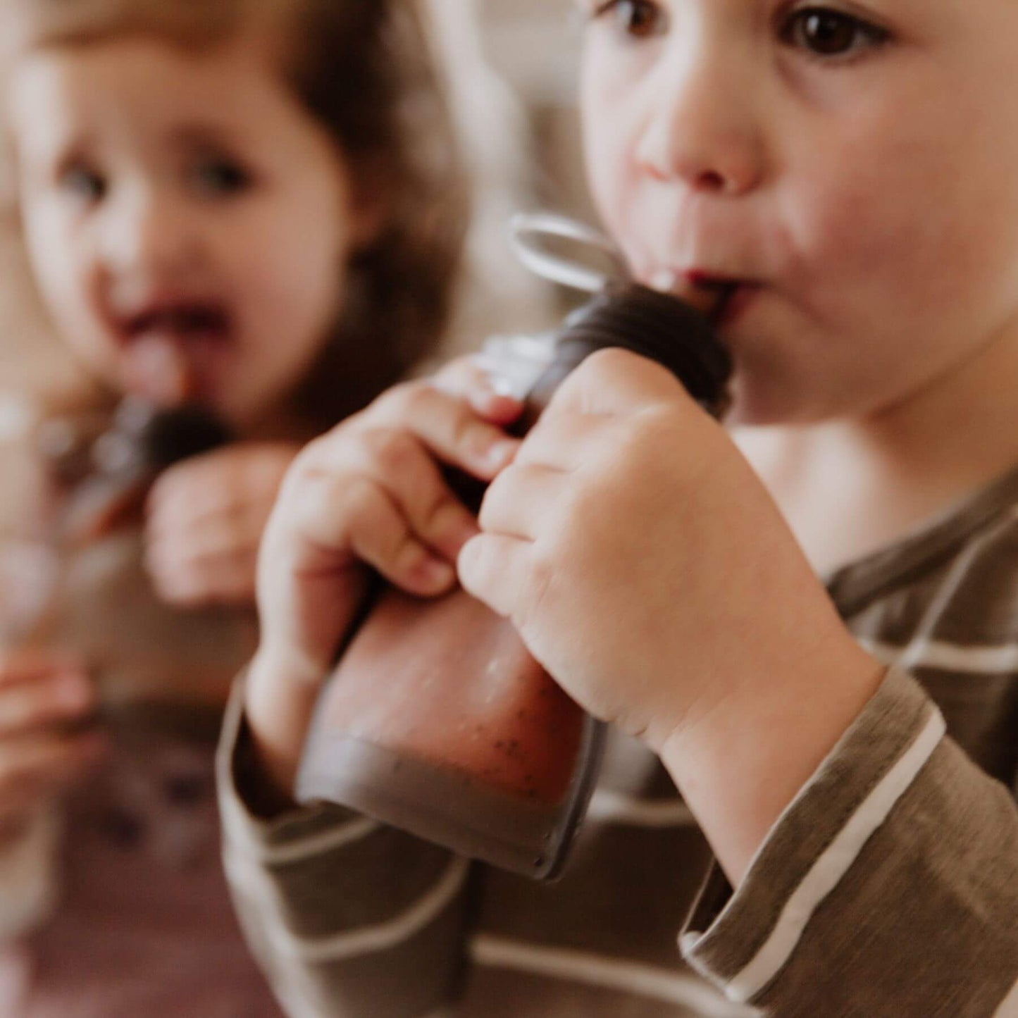 Two children drinking milk from Haakaa Milk Storage Bag