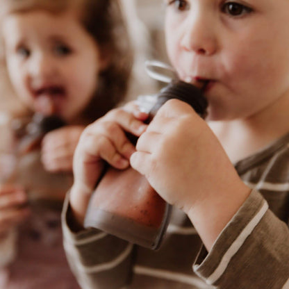 Two children drinking milk from Haakaa Milk Storage Bag