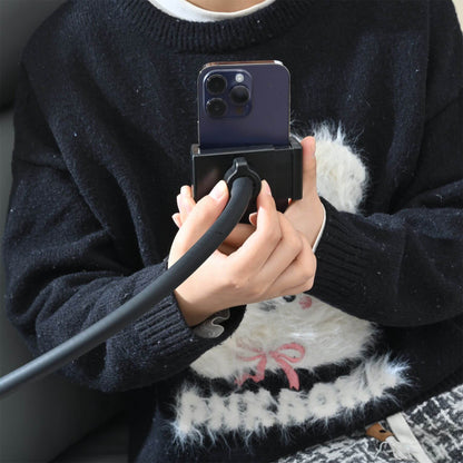 Person holding a phone with a selfie stick, wearing a dark sweater and white fur-lined jacket.