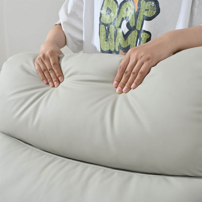 Person sitting on a large beige cushion with a white hoodie and green text visible.