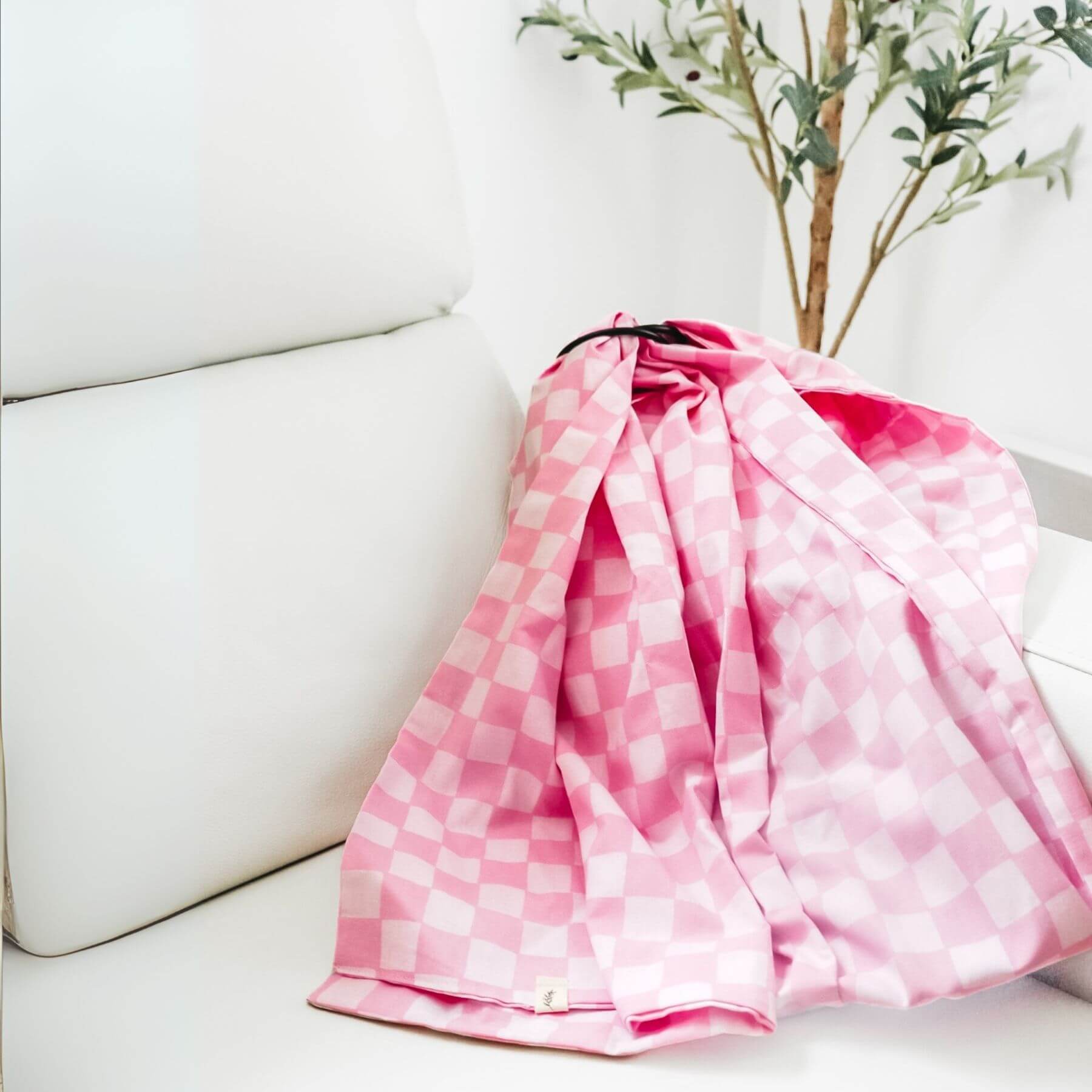 Little Mae & Co Sunkist Ring Sling Carrier draped over a white couch with a plant in the background