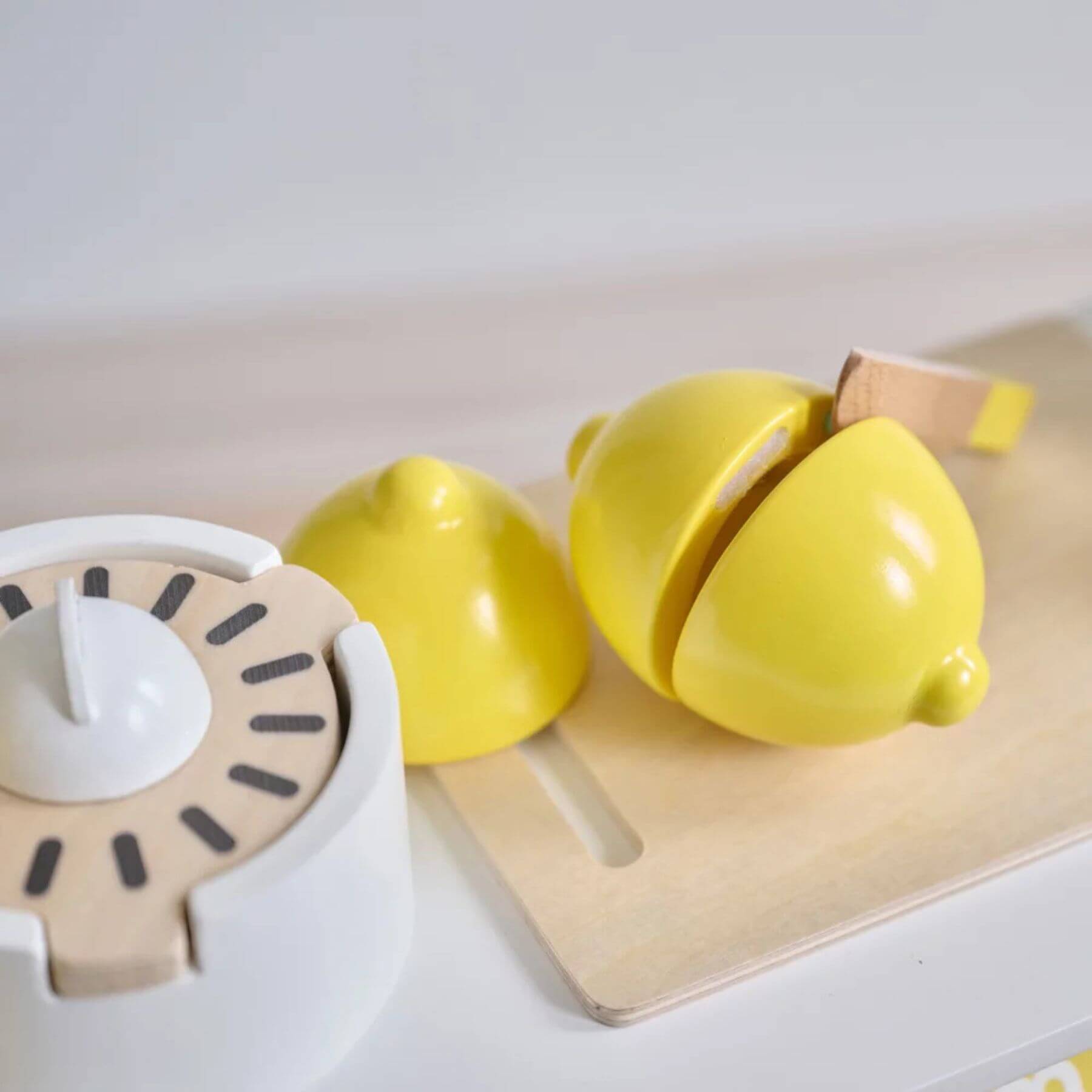 Yellow kitchen timer and lemon-shaped container on a white surface