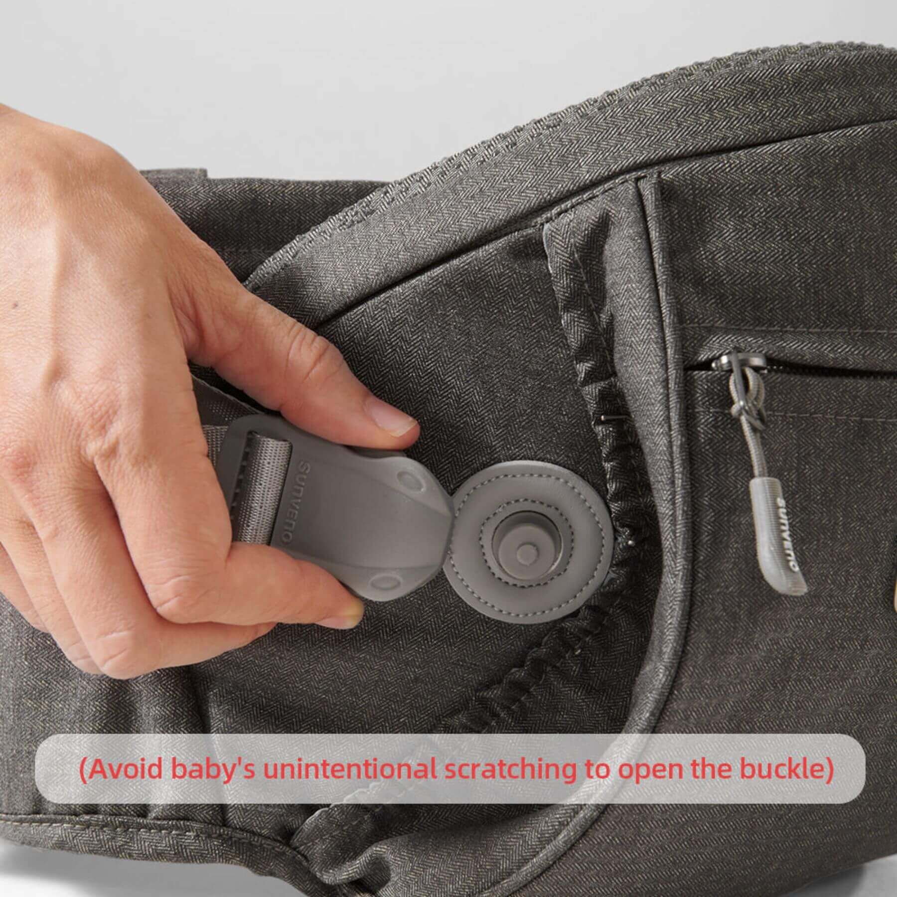 Hand adjusting a buckle on a gray baby carrier with text warning about unintentional scratching.