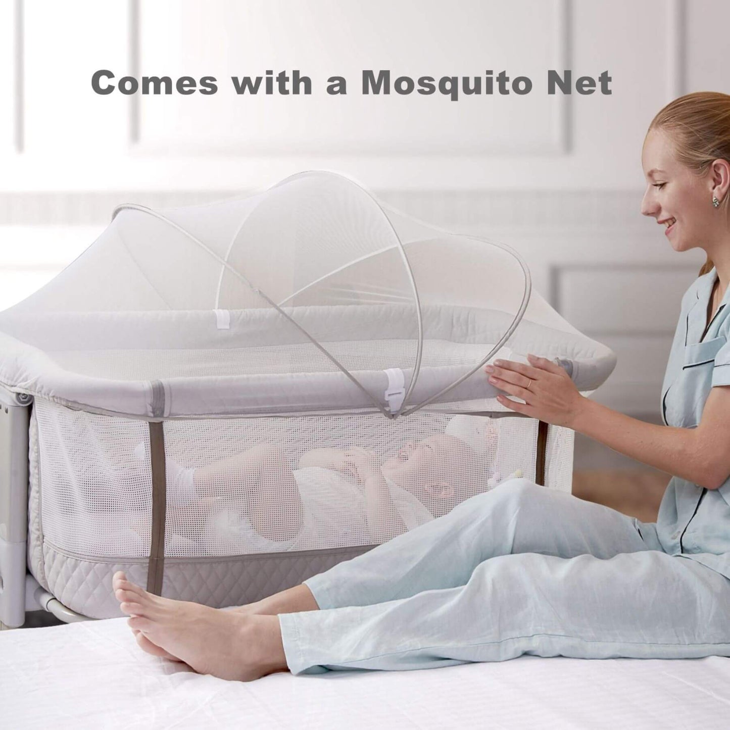 Woman sitting next to Sunveno Baby Bassinet Bedside Crib, indicating the crib comes with a mosquito net.