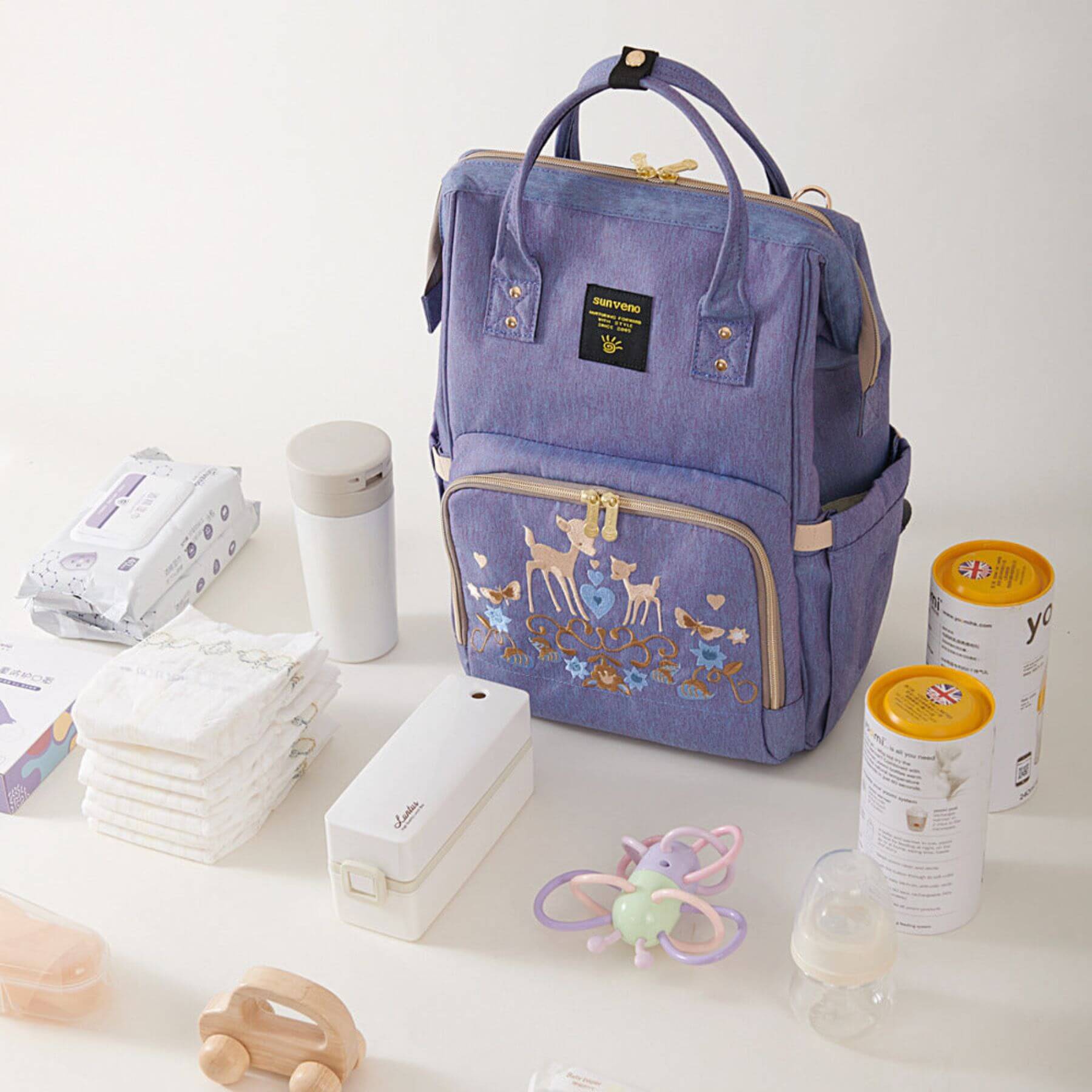 Sunveno Classic Embroidered Diaper Backpack - Purple Deer with baby items on a white surface