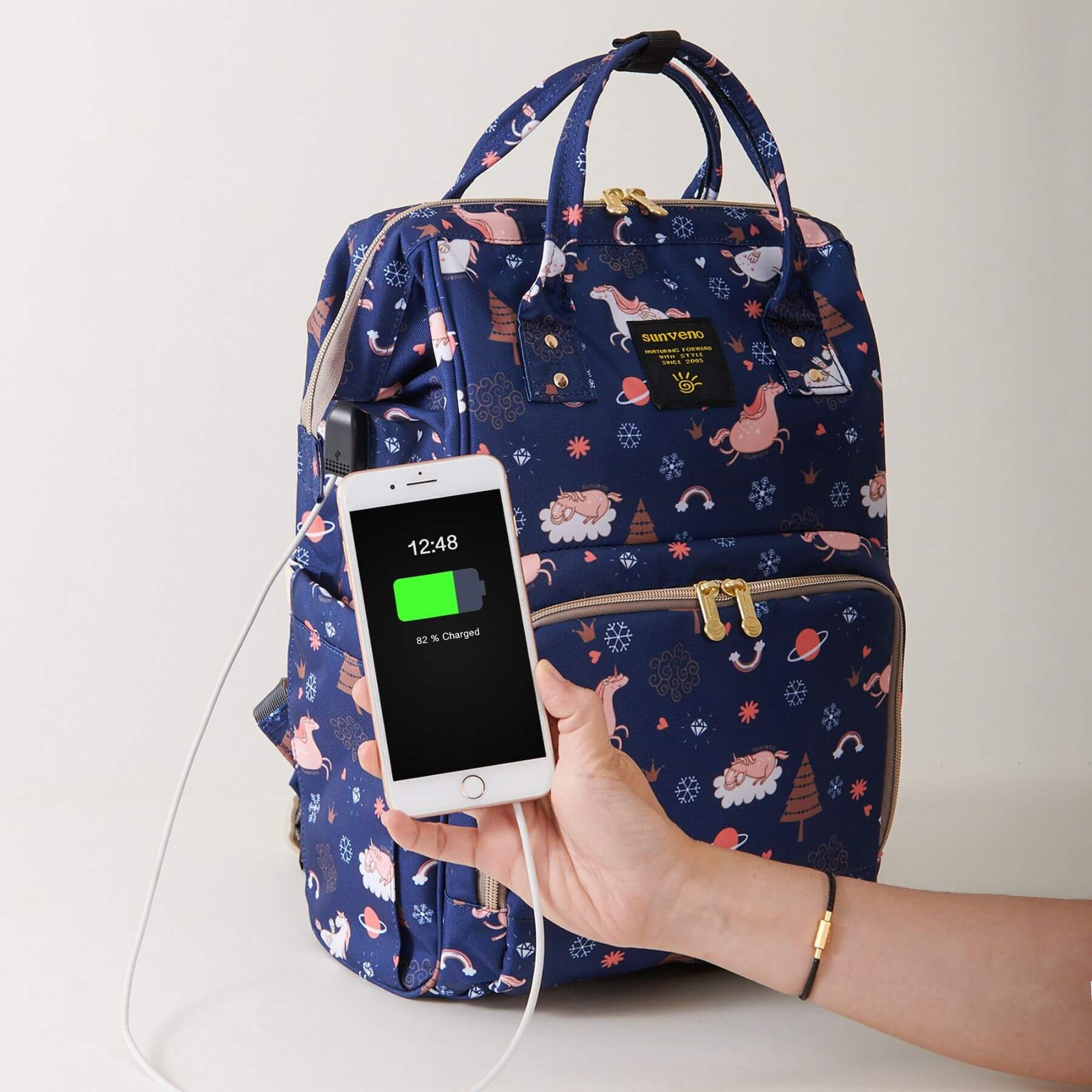 Sunveno Timeless Baby Diaper Backpack - Navy Unicorn with a Hand holding phone