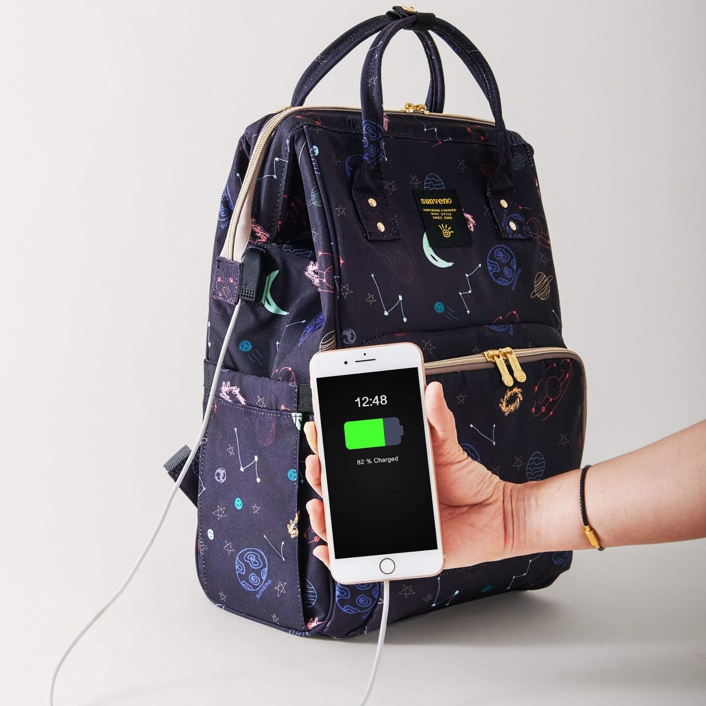 Sunveno Timeless Baby Diaper Backpack - Night Sky with hand holding a phone