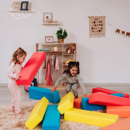 Two children playing with colorful foam blocks in a room with a shelf and decorations.