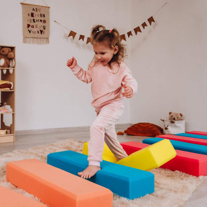 Child playing with colorful foam blocks in a room with educational decorations.