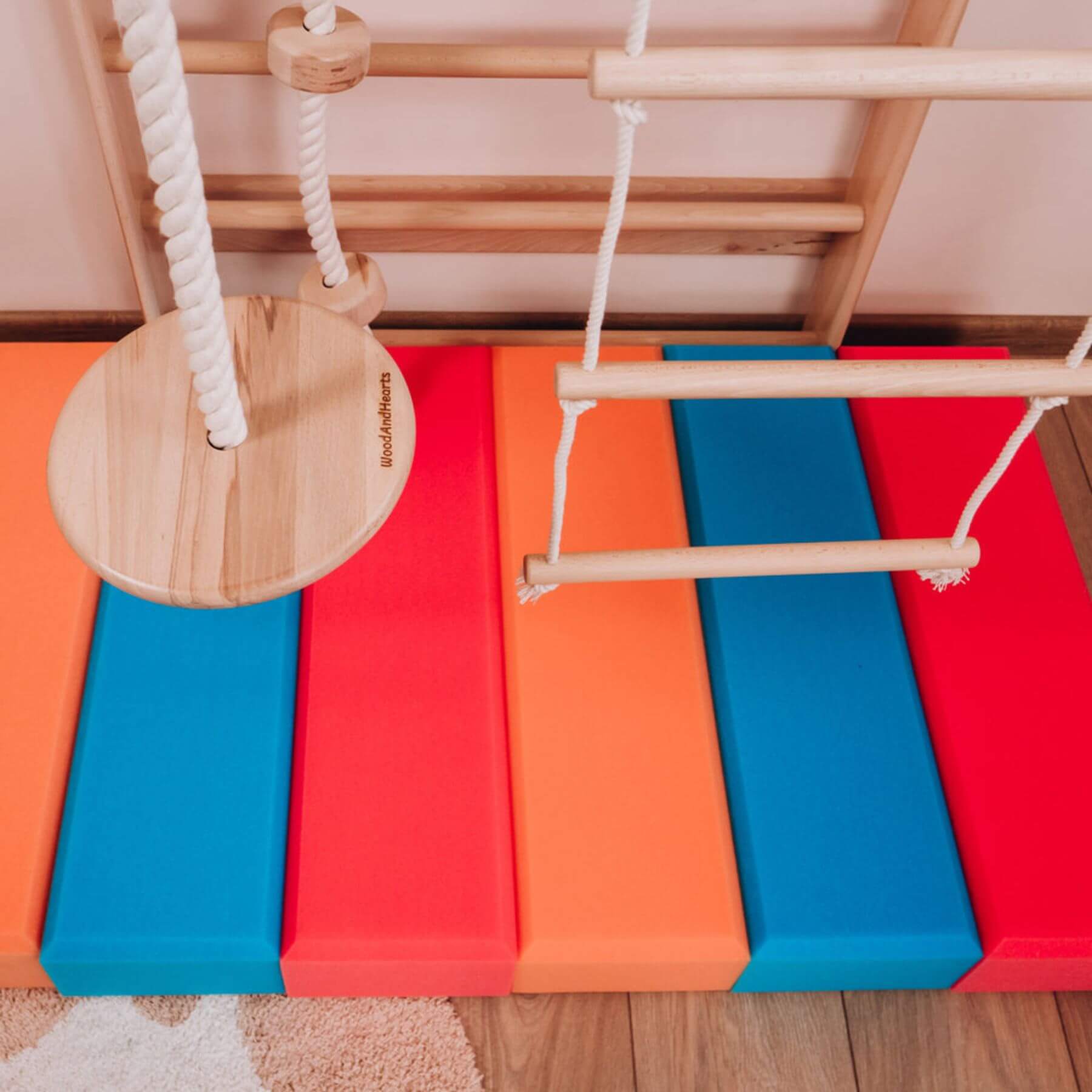 Children's play area with colorful mats and wooden climbing structure.
