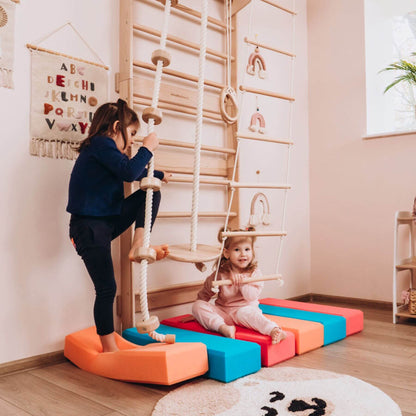 Two children playing on Wood and Hearts Swedish Ladder Gym on the floor.