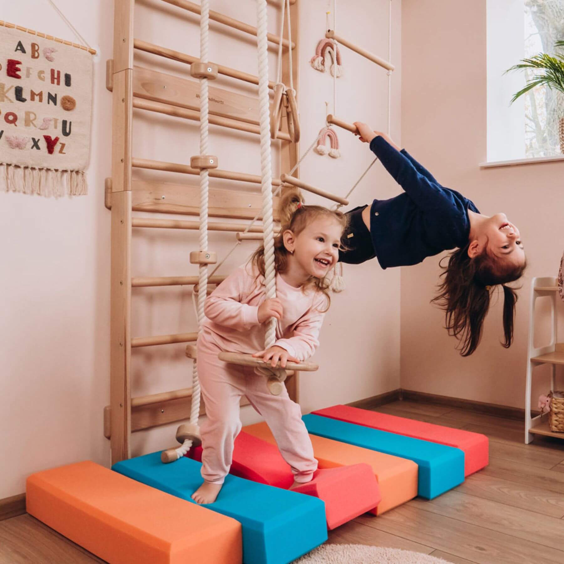Two children playing on Wood and Hearts Swedish Ladder Gym on the floor.