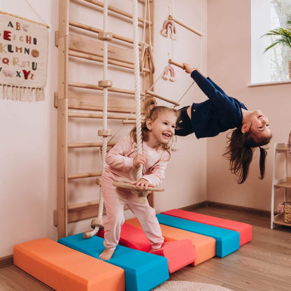 Two children playing on Wood and Hearts Swedish Ladder Gym on the floor.