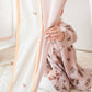 Child's hand holding a curtain rod with a floral-patterned outfit