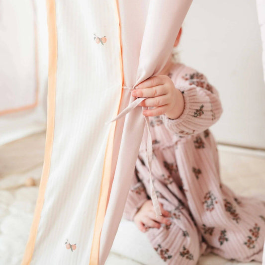 Child's hand holding a curtain rod with a floral-patterned outfit