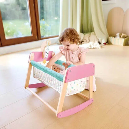 Child playing with a doll in Hape Sweet Dreams Doll's Bed in a bright room.