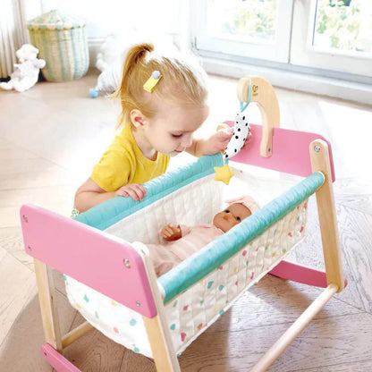 Child playing with a doll in Hape Sweet Dreams Doll's Bed in a bright room.