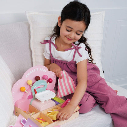 Young girl playing with Tender Leaf Sweetie Pic'n'Mix Shop on a white couch.