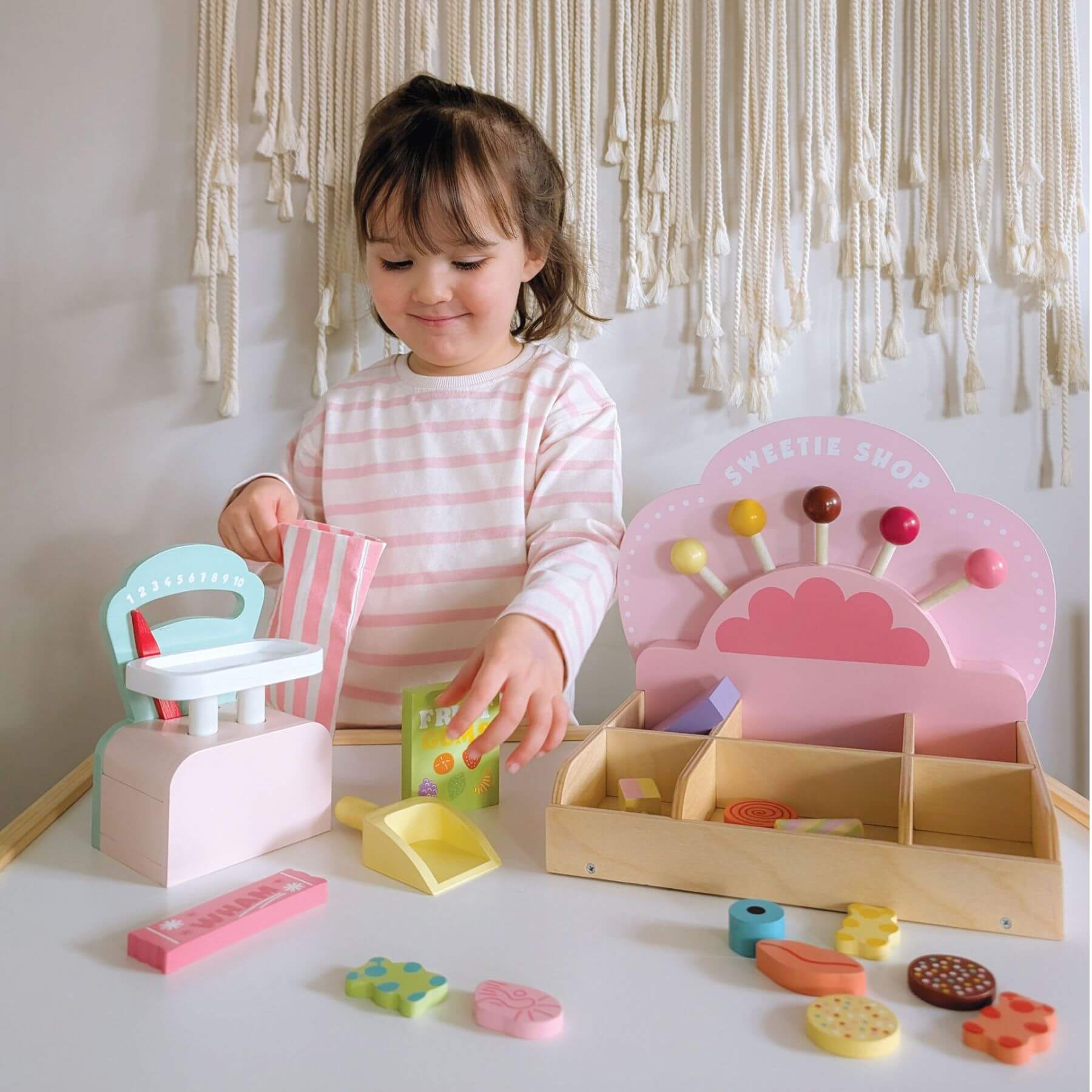 Child playing with Tender Leaf Sweetie Pic'n'Mix Shop on a white surface.