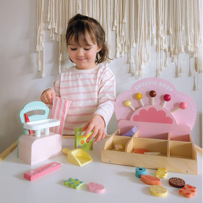 Child playing with Tender Leaf Sweetie Pic'n'Mix Shop on a white surface.
