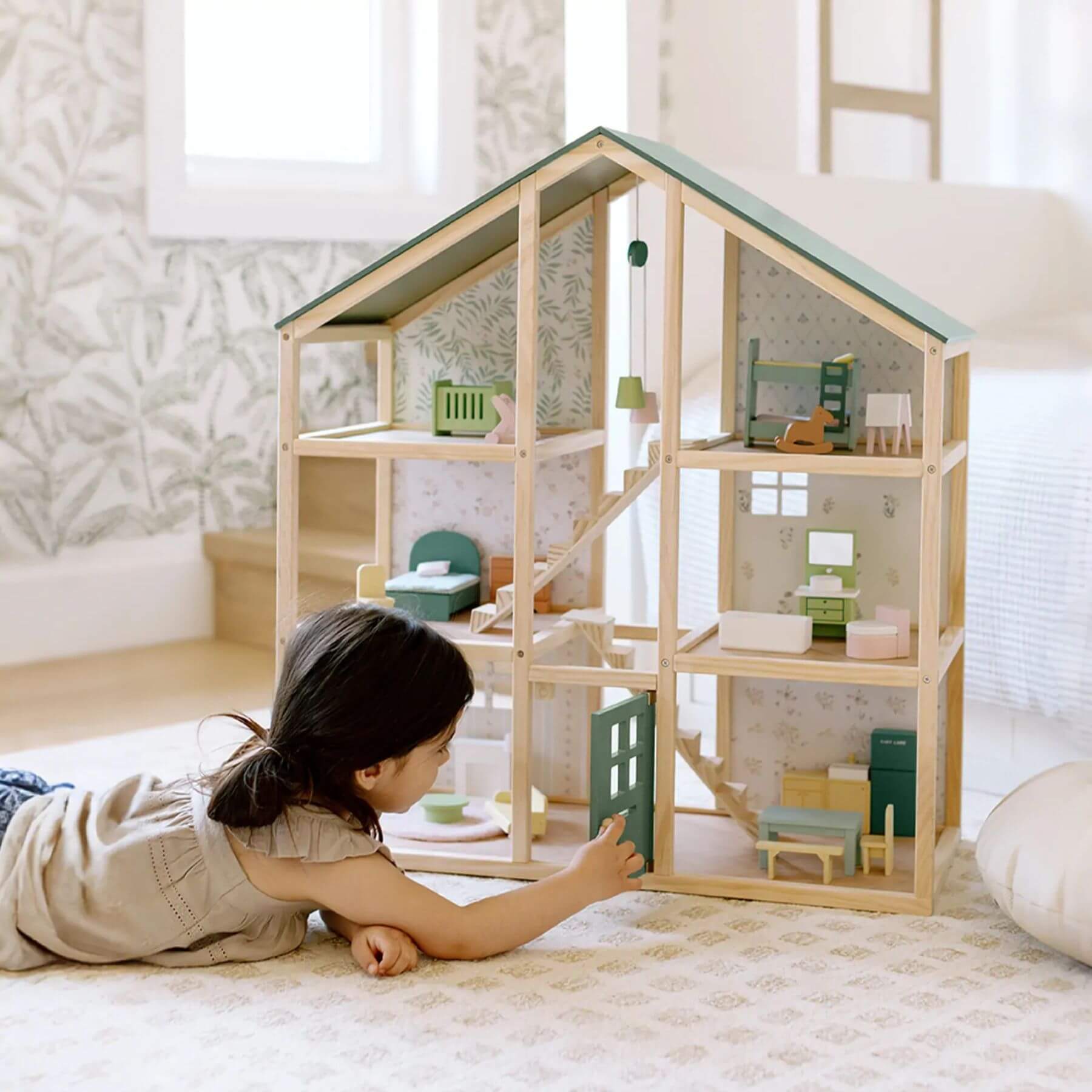Child playing with Sweetwood Evergreen Dollhouse in a bright room.