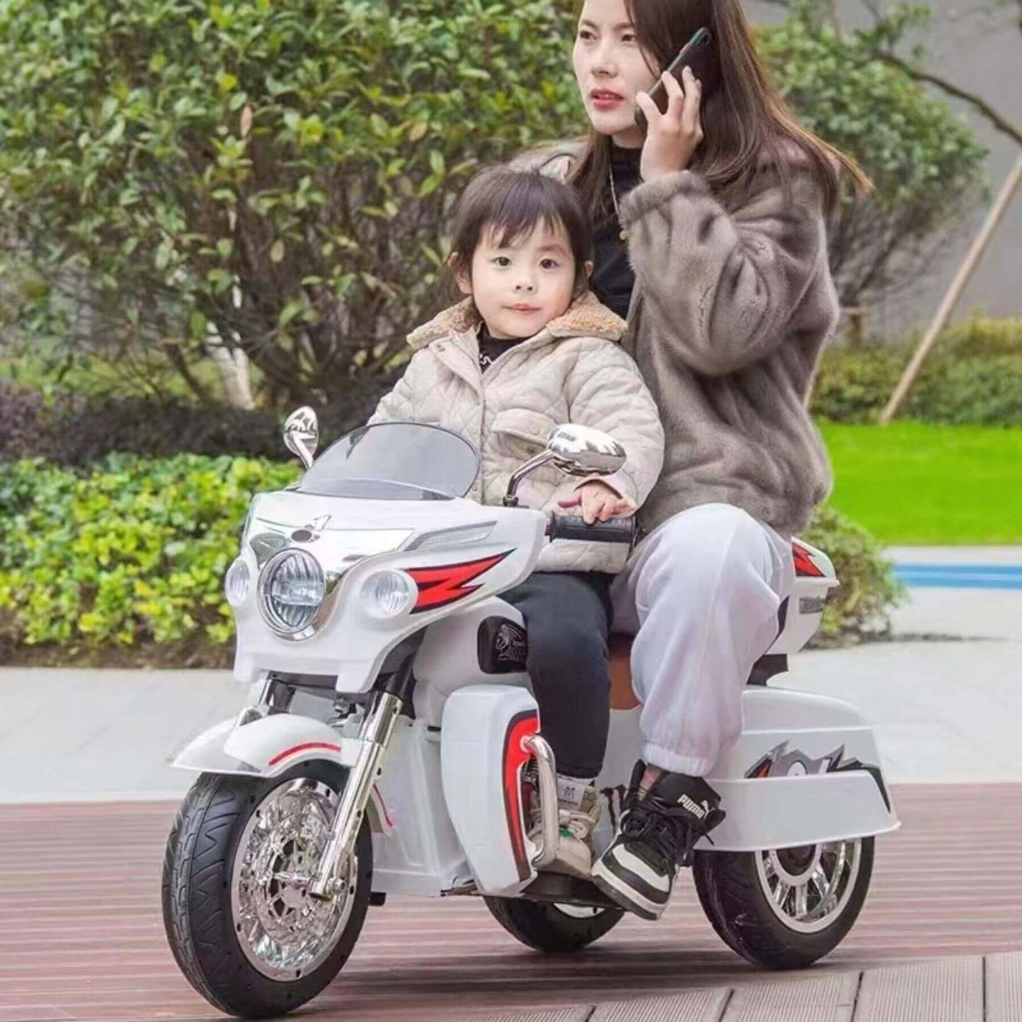 Woman and child riding Tamco 12V Kids Electric Ride On Motorcycle - White outdoors.