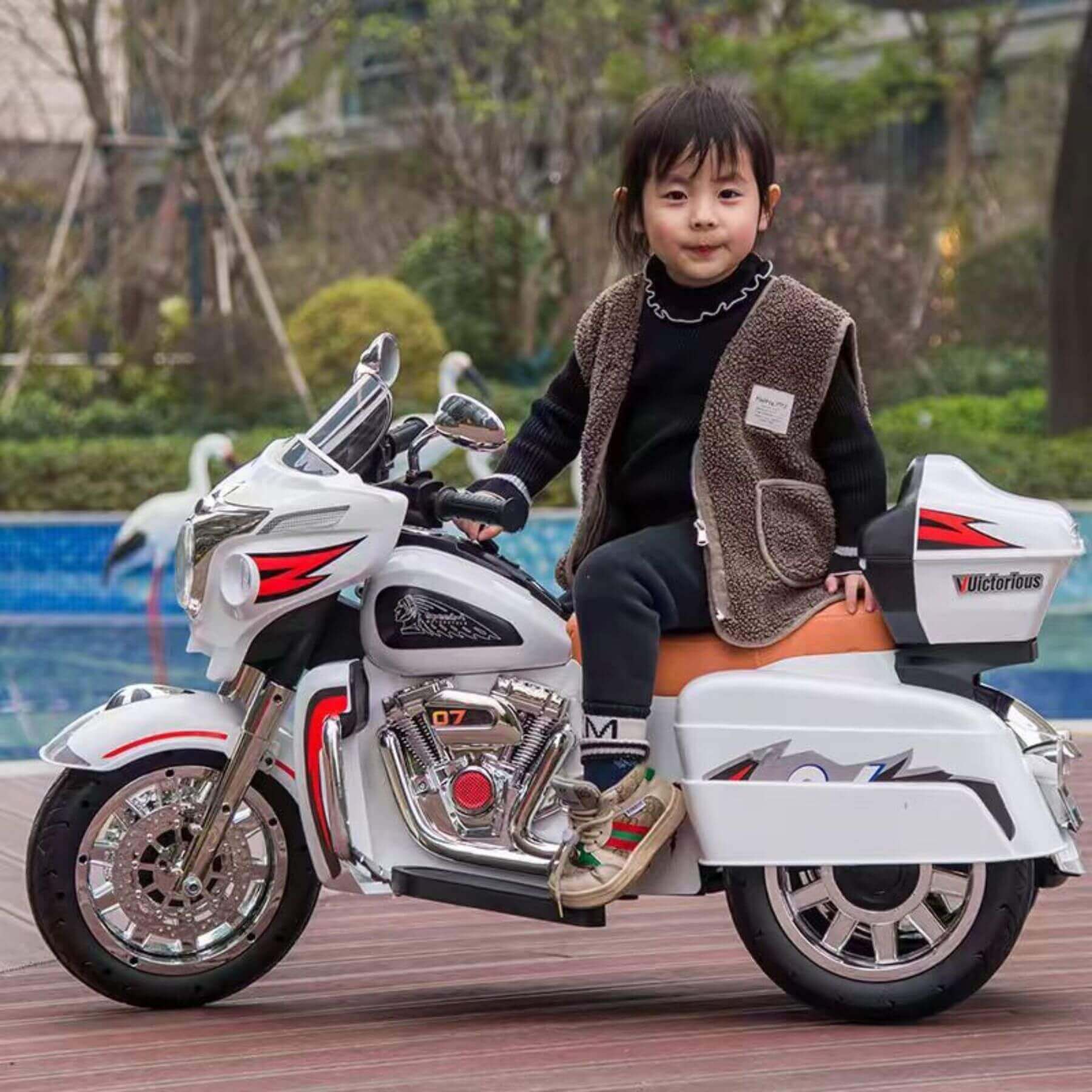 Child sitting on Tamco 12V Kids Electric Ride On Motorcycle - White in an outdoor setting