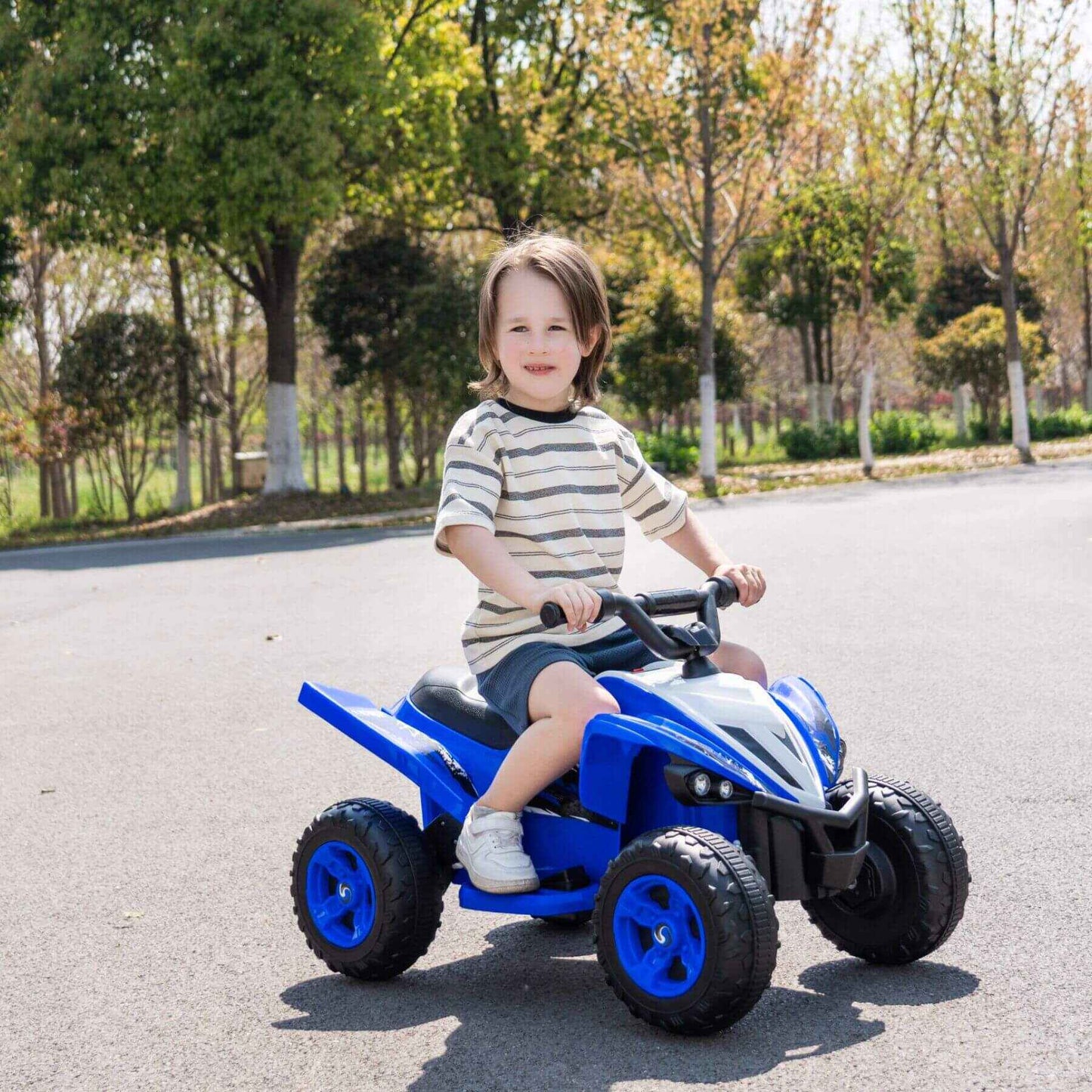 Child riding Tamco Kids Dual Motor Electric Ride On Toy - Blue on a paved road with trees in the background