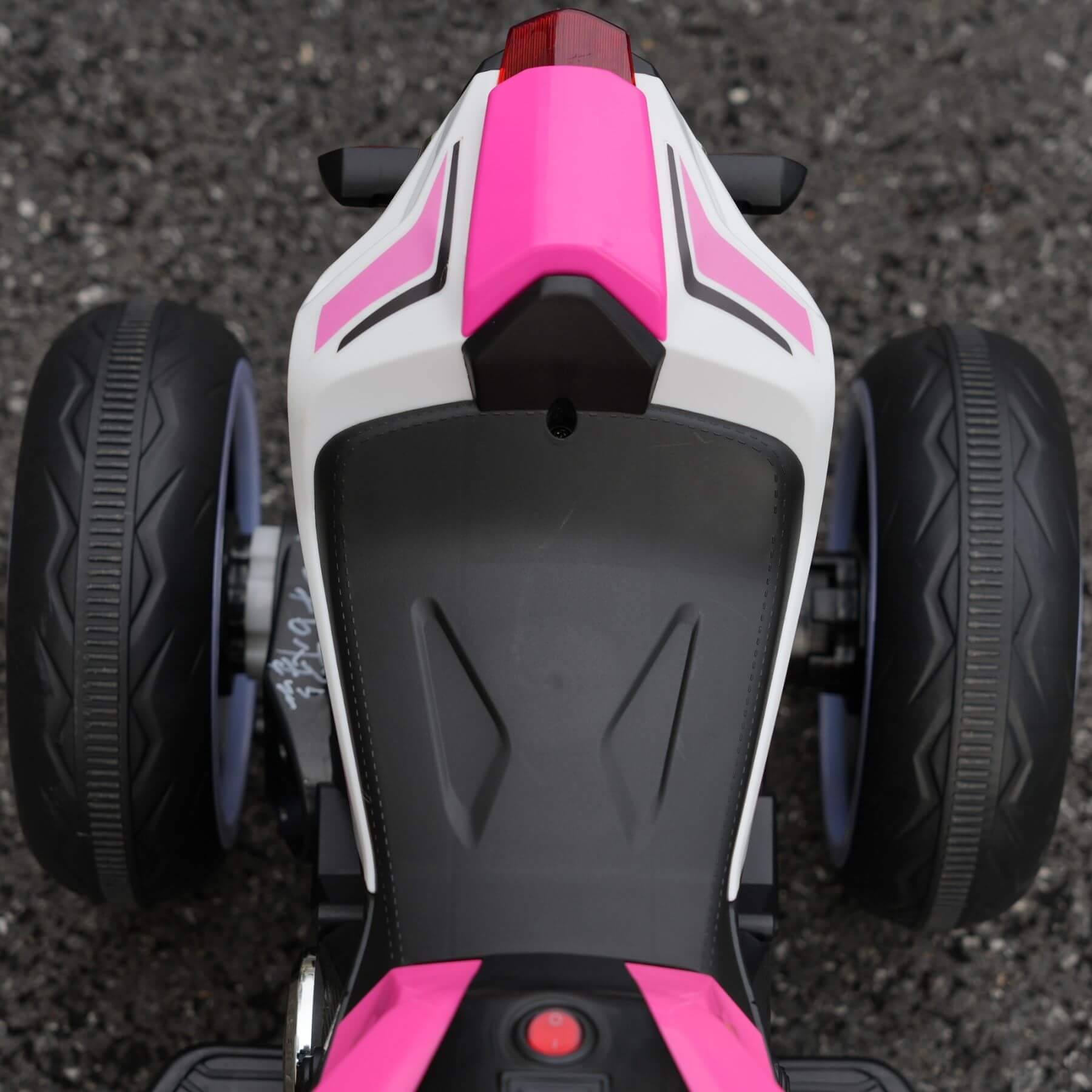 Close-up of a pink and white toy motorcycle on a dark surface