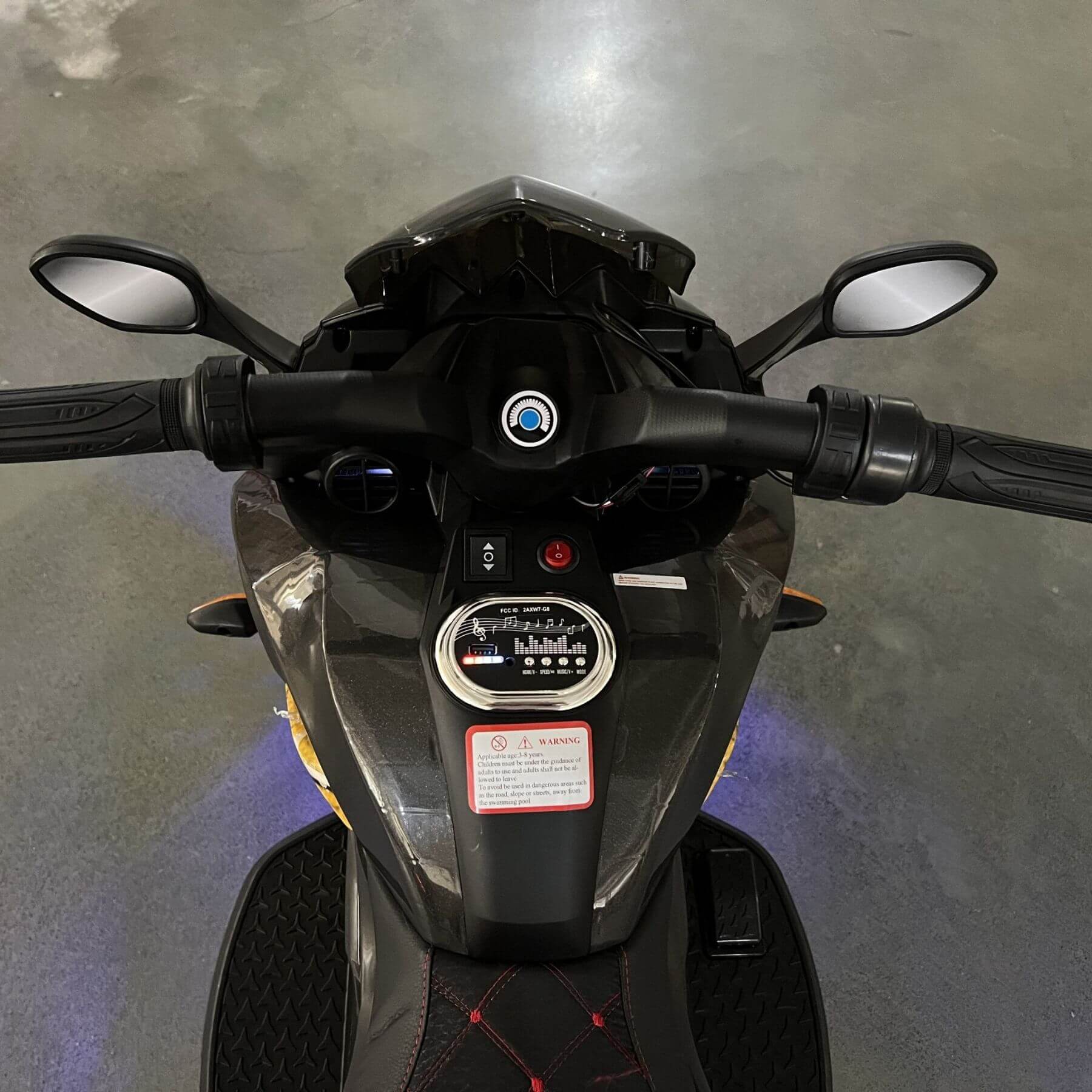 Close-up of a motorcycle's handlebar and front section on a gray floor.