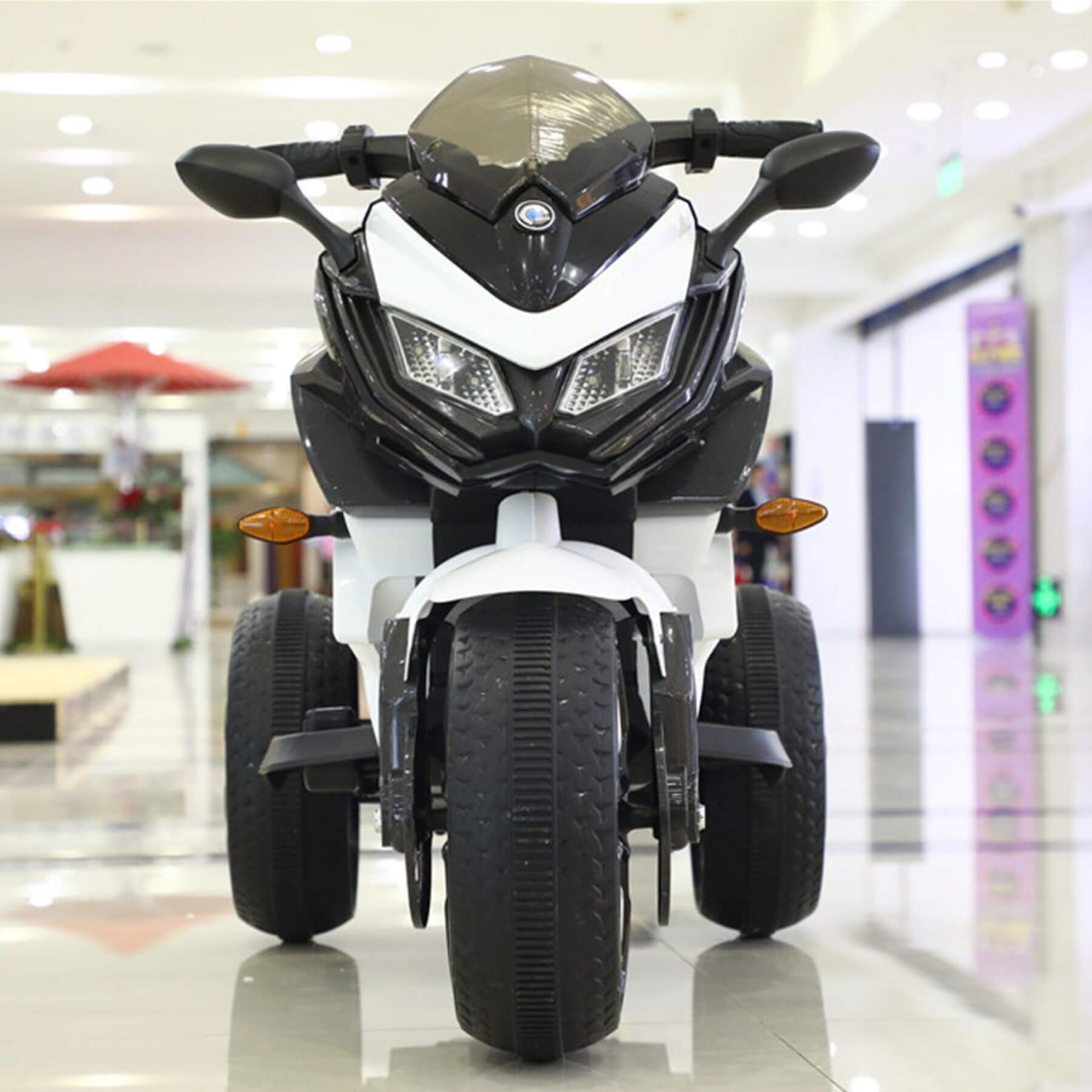 Children's toy motorcycle with BMW logo in a mall setting
