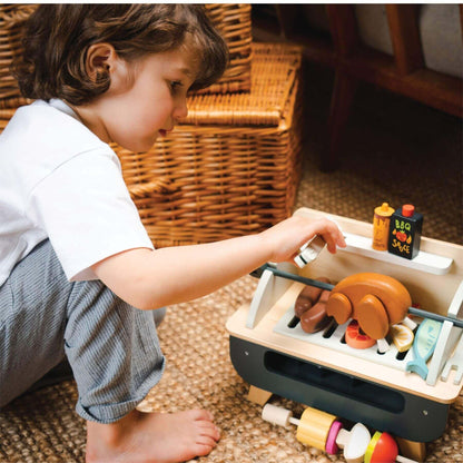 Child playing with Tender Leaf Barbeque Play Set on a carpeted floor.
