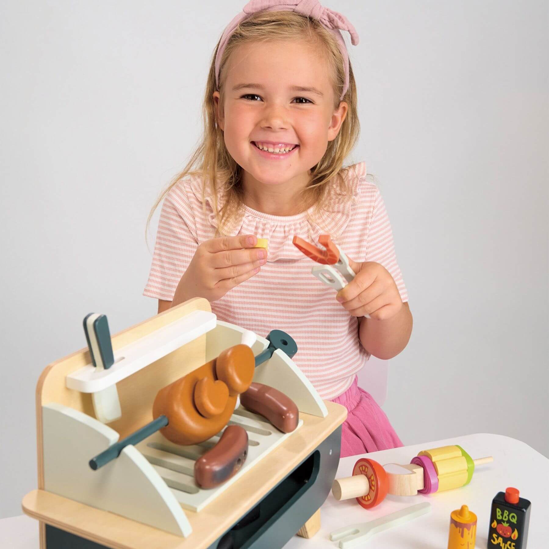 Child playing with Tender Leaf Barbeque Play Set on a white table