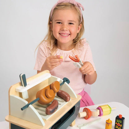 Child playing with Tender Leaf Barbeque Play Set on a white table