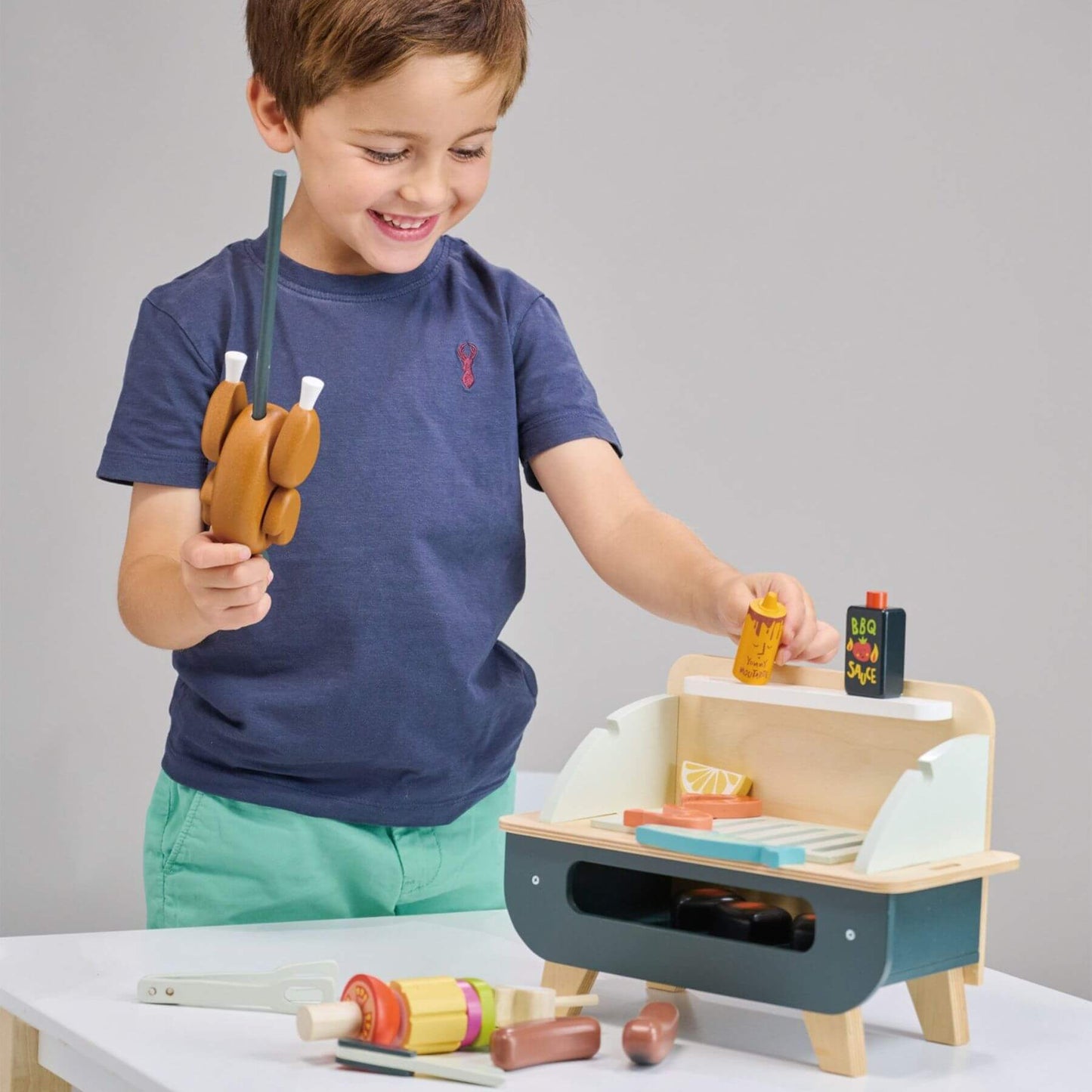Child playing with Tender Leaf Barbeque Play Set on a gray background