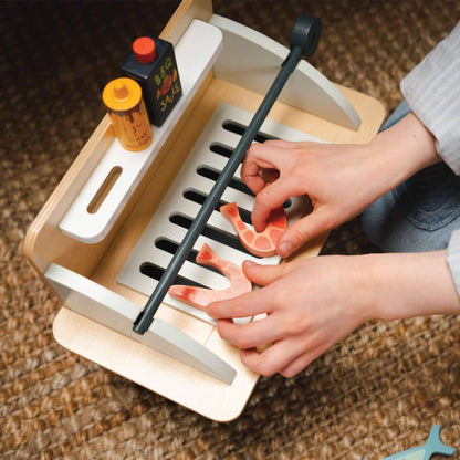 Child playing with Tender Leaf Barbeque Play Set on a woven surface