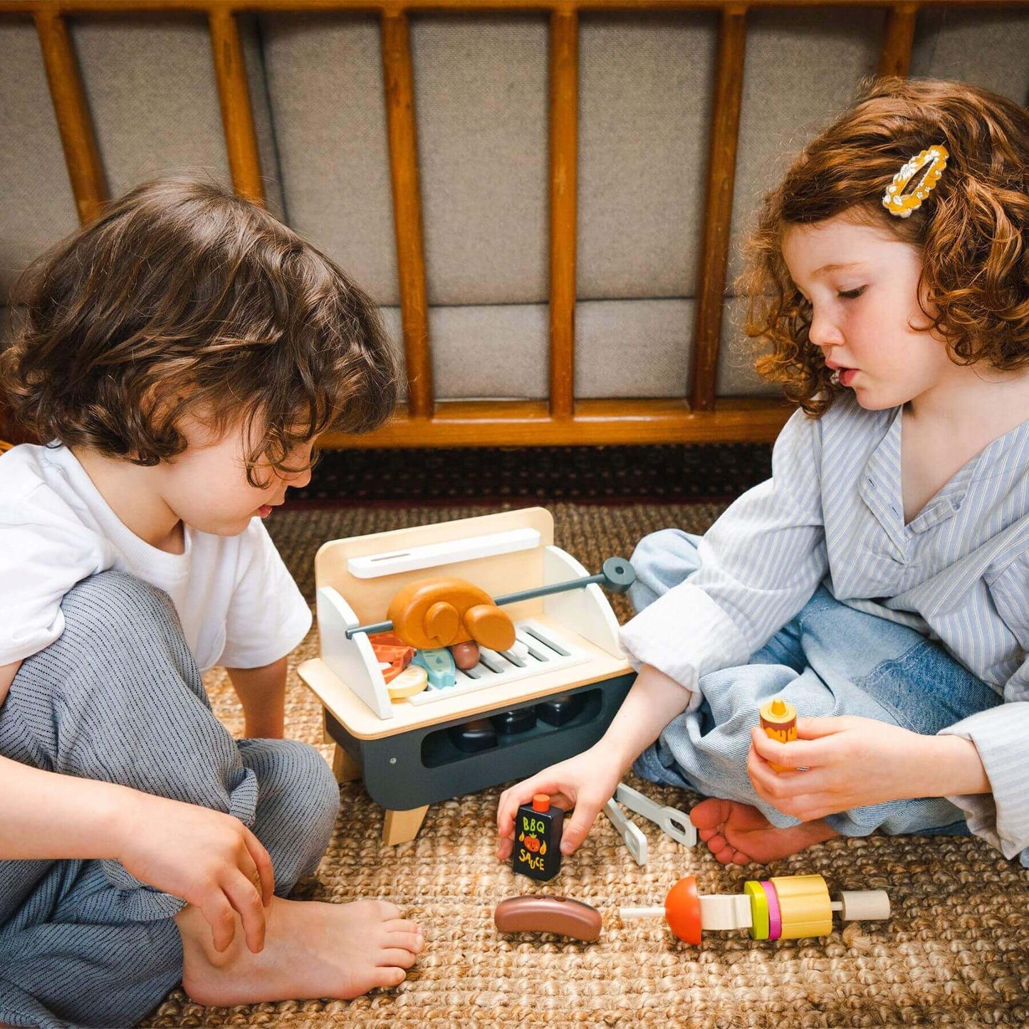 Two children playing with Tender Leaf Barbeque Play Set on the floor.
