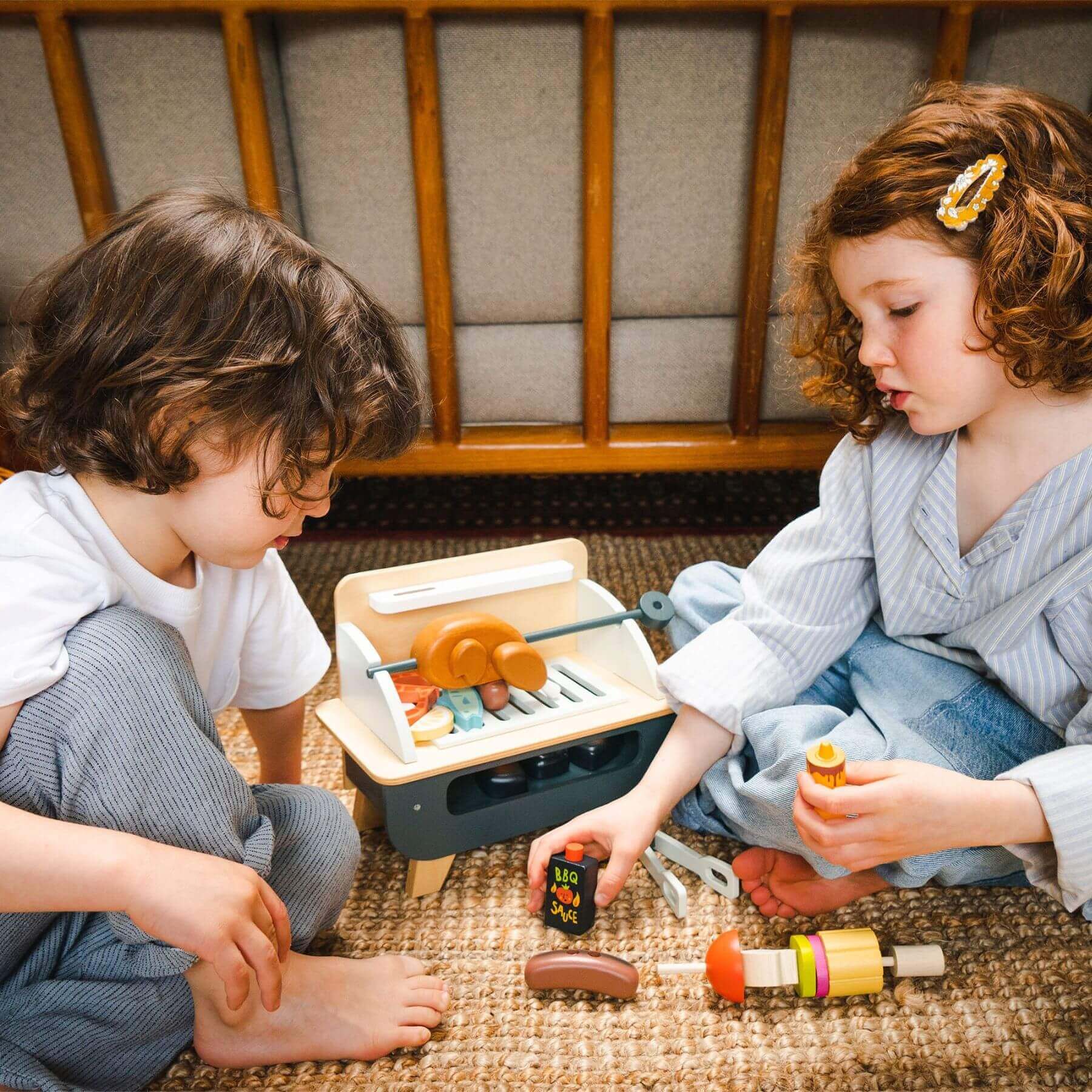 Two children playing with Tender Leaf Barbeque Play Set on the floor.