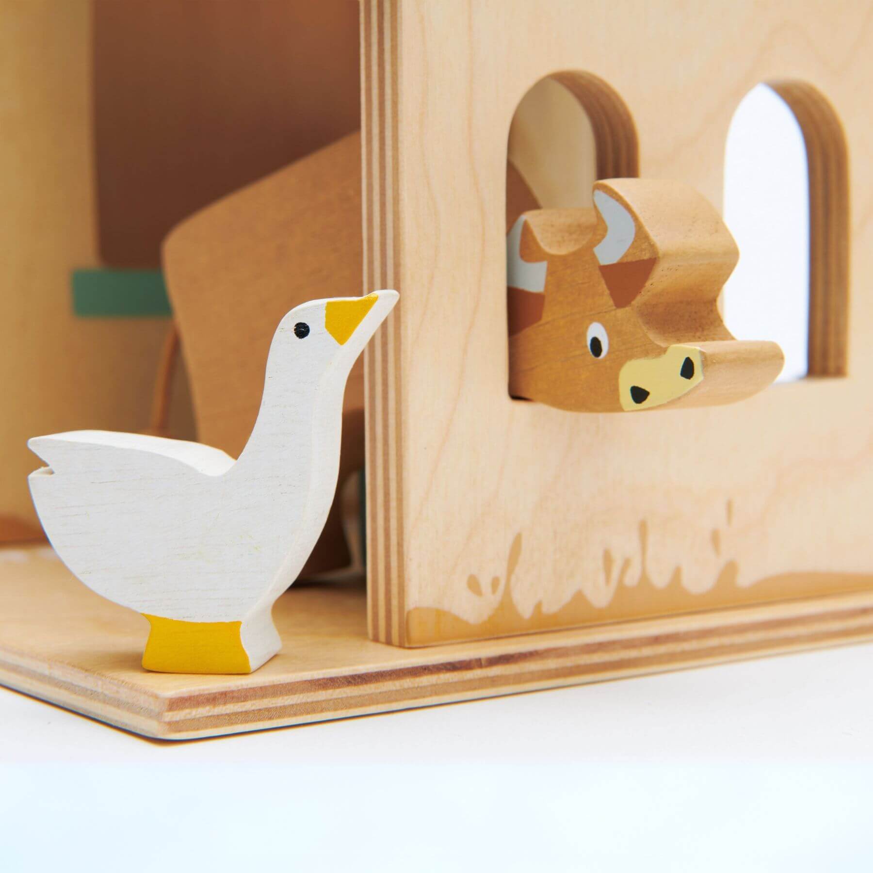Wooden toy with a goose figure and a cow figure peeking out of a wooden block.