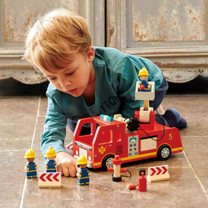 Child playing with Tender Leaf Fire Engine on a wooden floor.