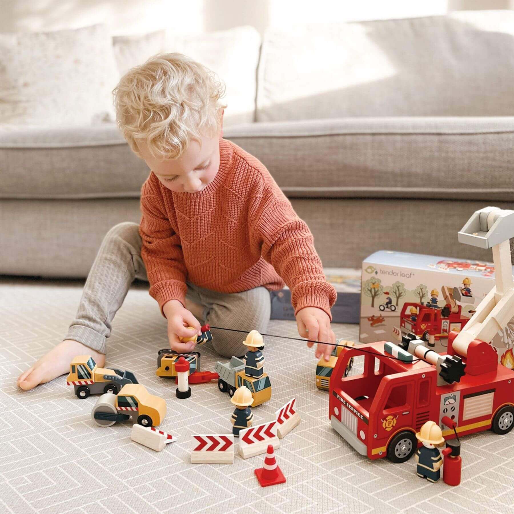 Child playing with Tender Leaf Fire Engine on a tiled floor.