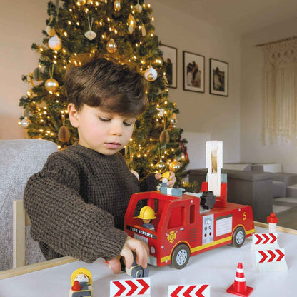 Child playing with Tender Leaf Fire Engine in front of a decorated Christmas tree.