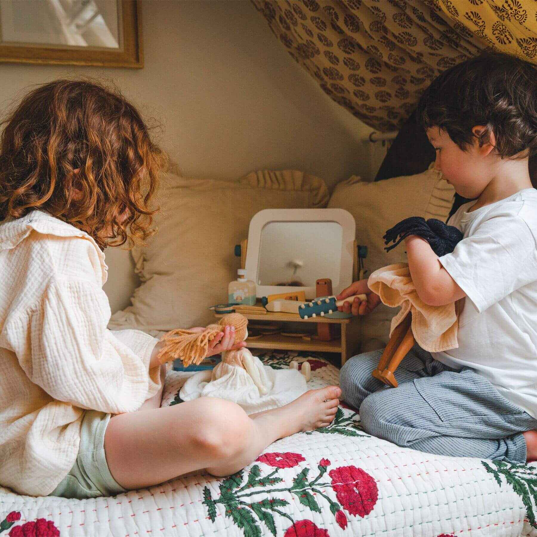 Two children playing with Tender Leaf Hair Salon on a bed in a cozy room.