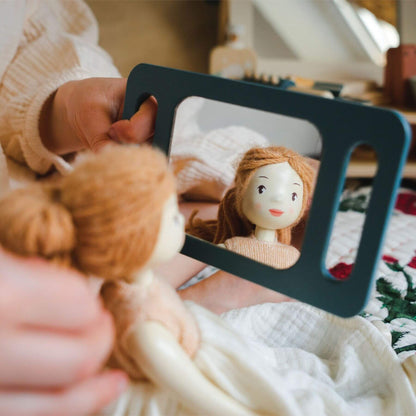 Person holding a knitted doll with a mirror