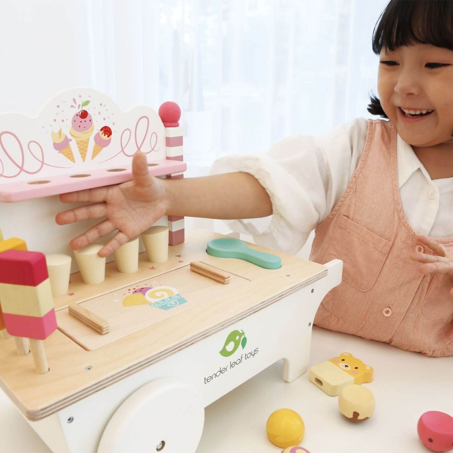 Child playing with Tender Leaf Ice Cream Cart, on a white surface.