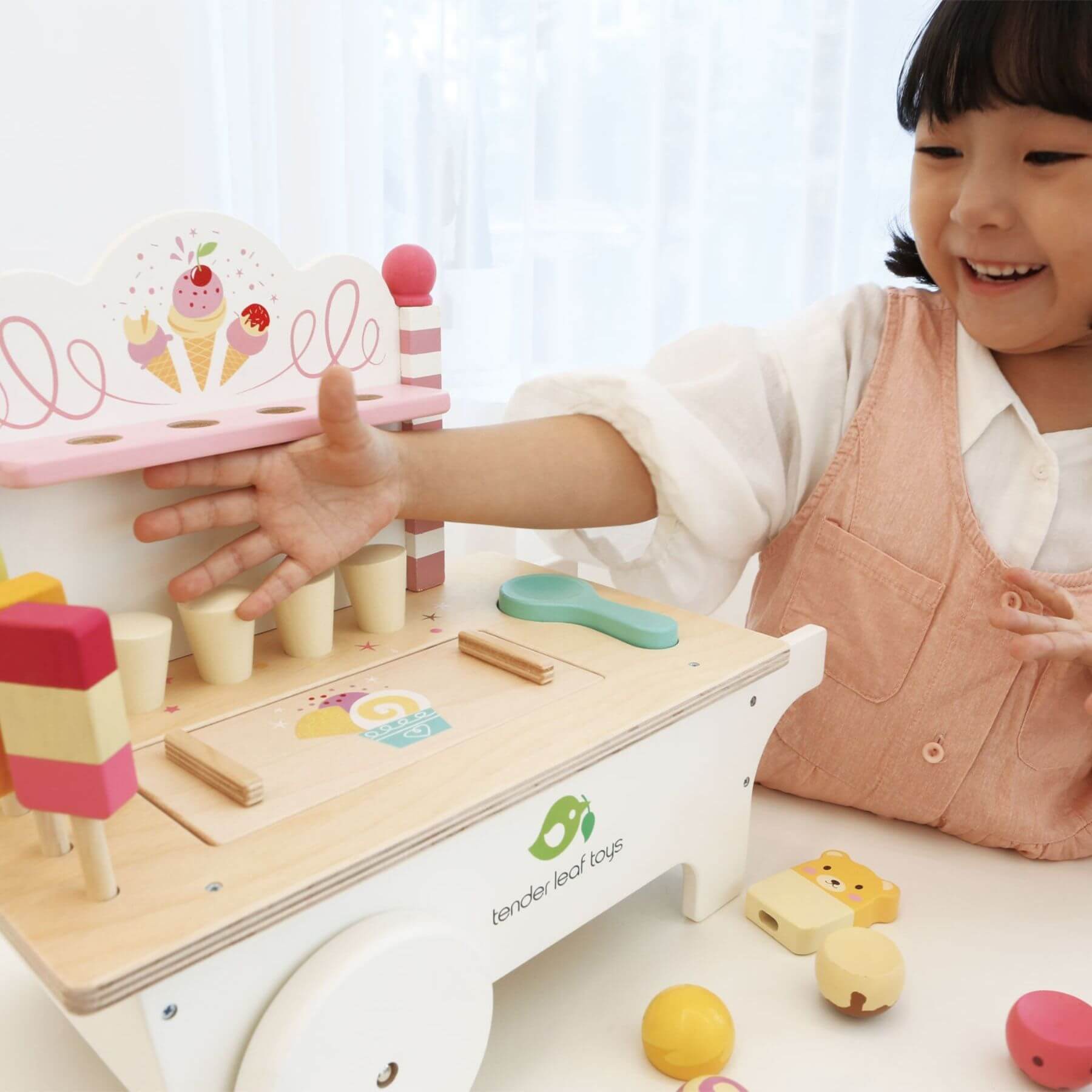 Child playing with Tender Leaf Ice Cream Cart, on a white surface.
