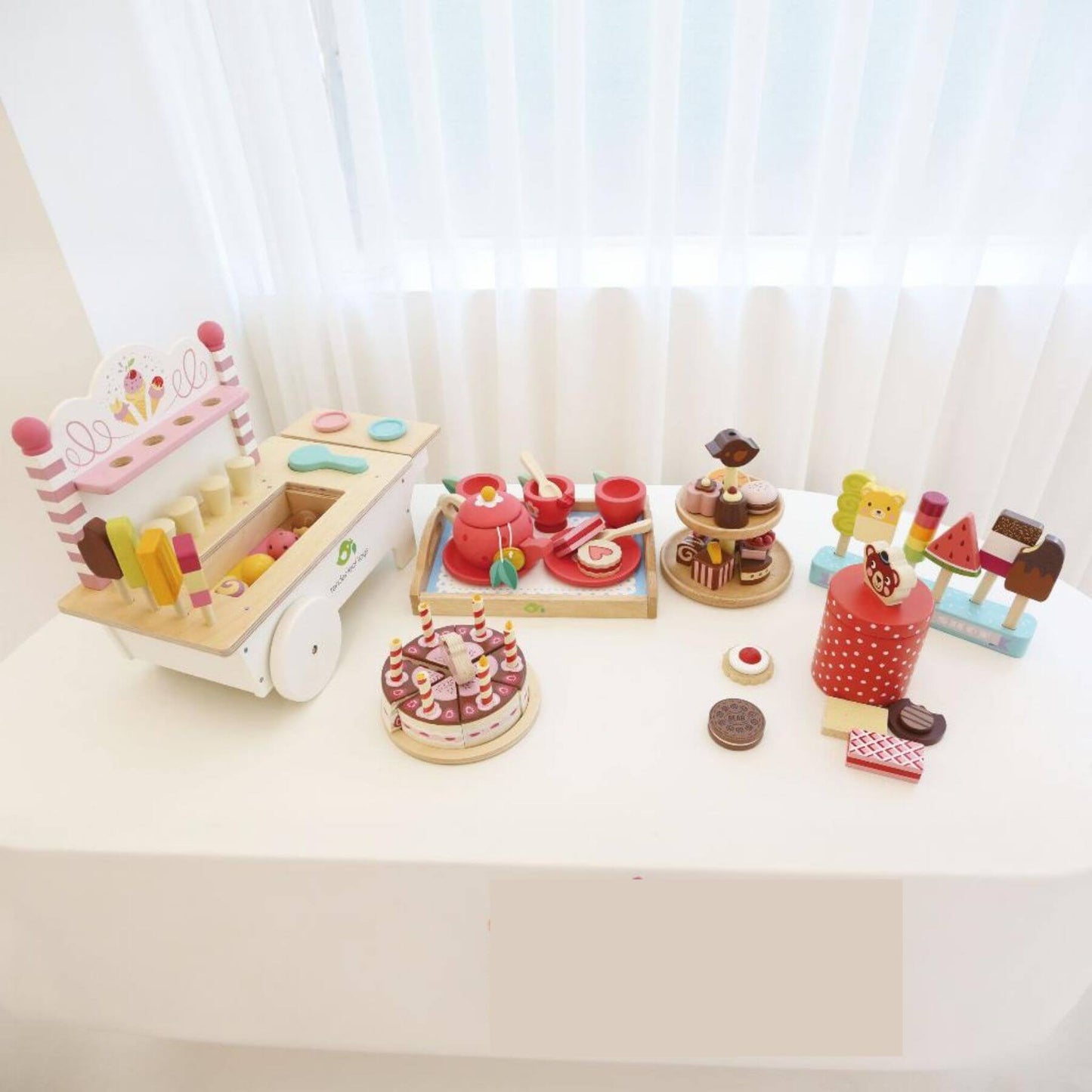 Set of wooden toy desserts on a white surface with a light background