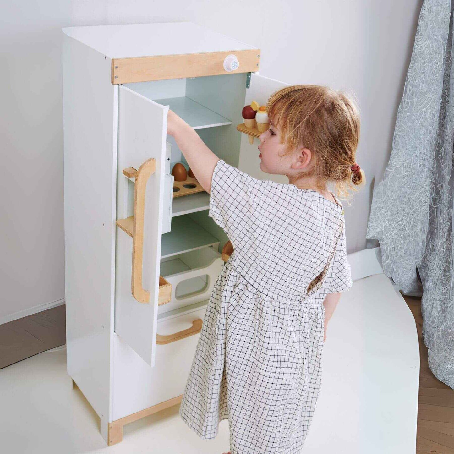 Child playing with Tender Leaf Refrigerator in a minimalistic room.