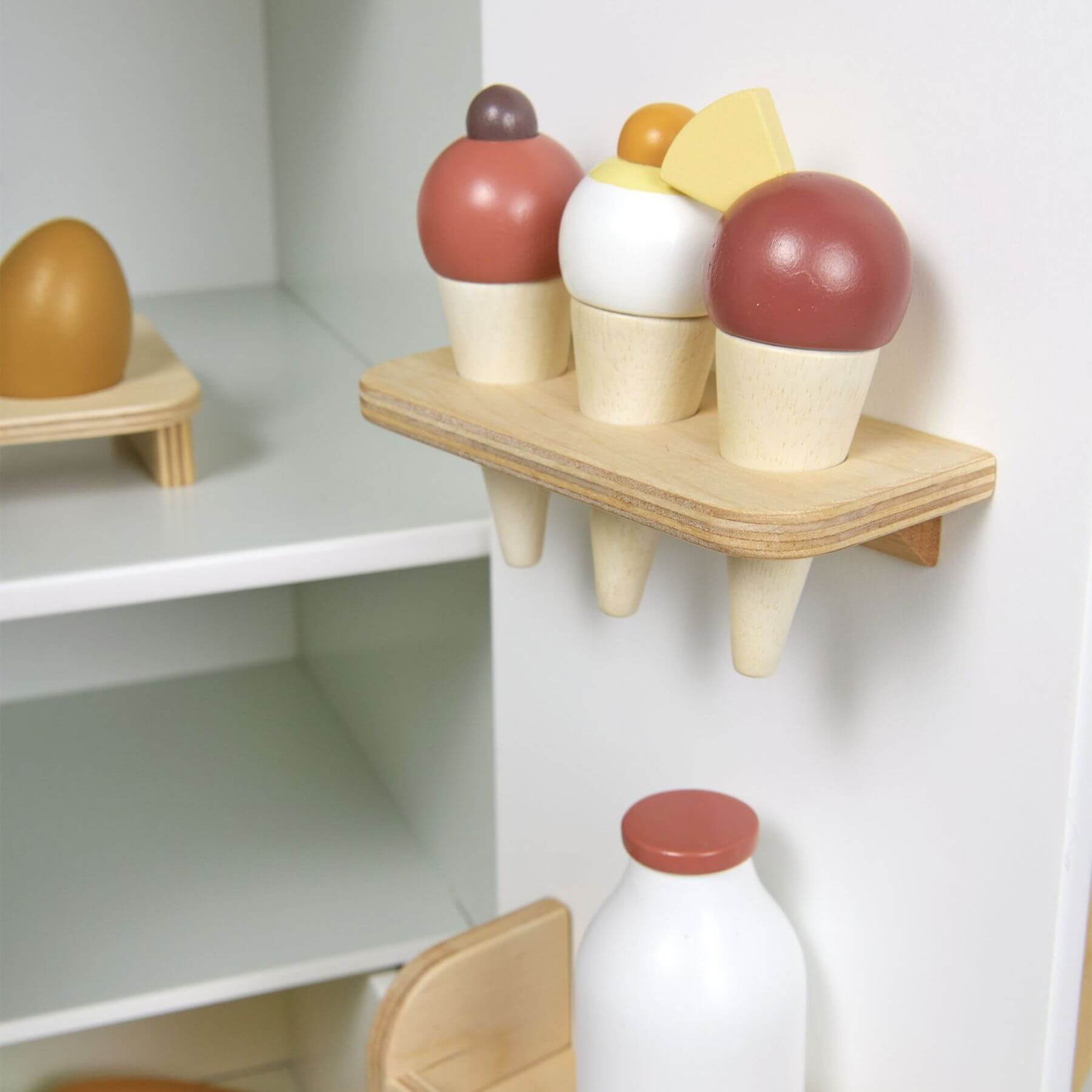 Colorful wooden ice cream cones and a bottle on a white shelf